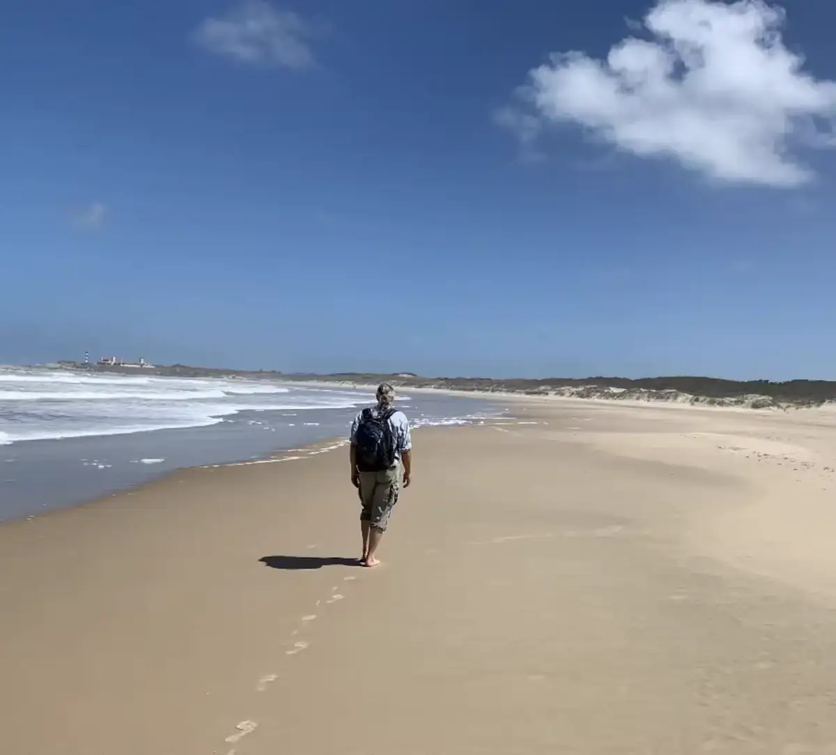 Caminante solo por una playa virgen de arena abierta