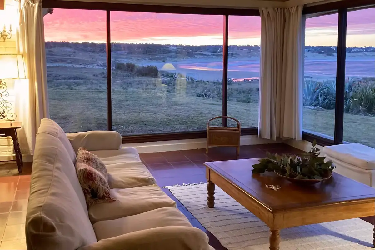 Interior de la residencia con ventanales de piso a techo al océano Atlántico al atardecer