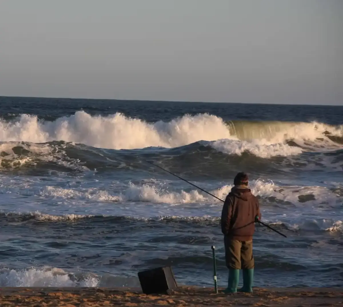 Pescador frente a las olas en la costa