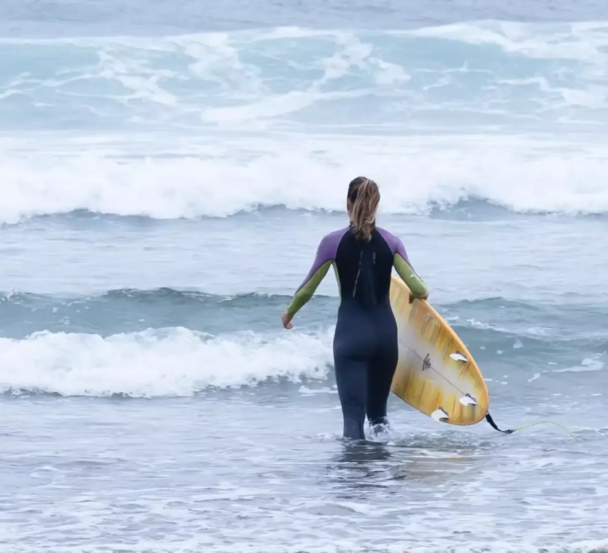 Surfista entrando al mar con su tabla