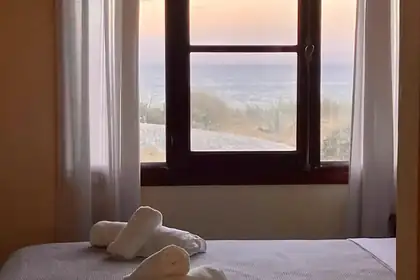 Dormitorio con ventana al mar y toallas dobladas sobre la cama