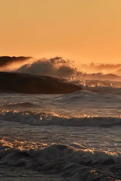 Ola rompiendo con luz anaranjada del atardecer